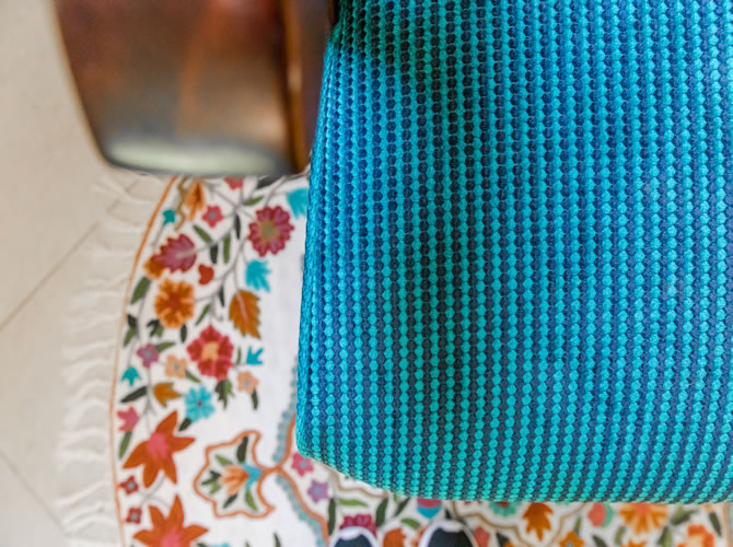 מבט מקרוב לבד הכורסא המחודשת בשילוב עם השטיח הצבעוני בפינת הקריאה.