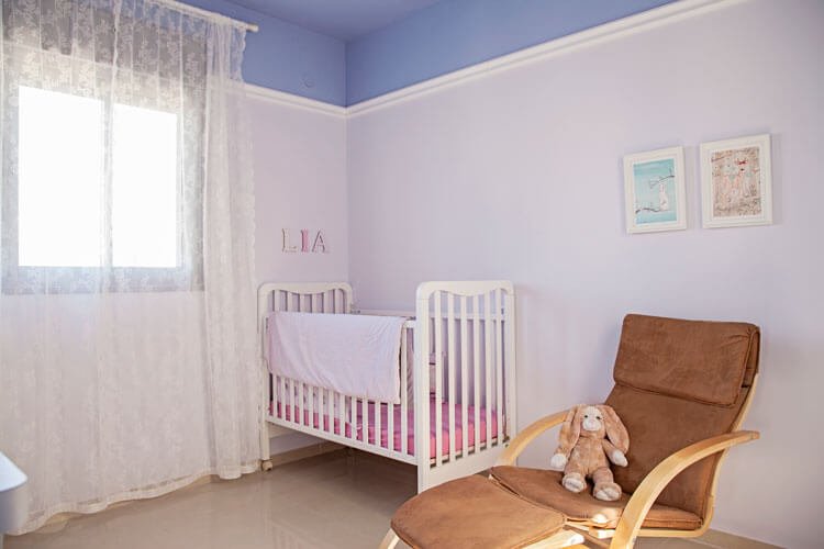 חדר של תינוקת בעיצוב נקי בשילוב קרניז וצביעה יחודית של הקירות והתקרה. 