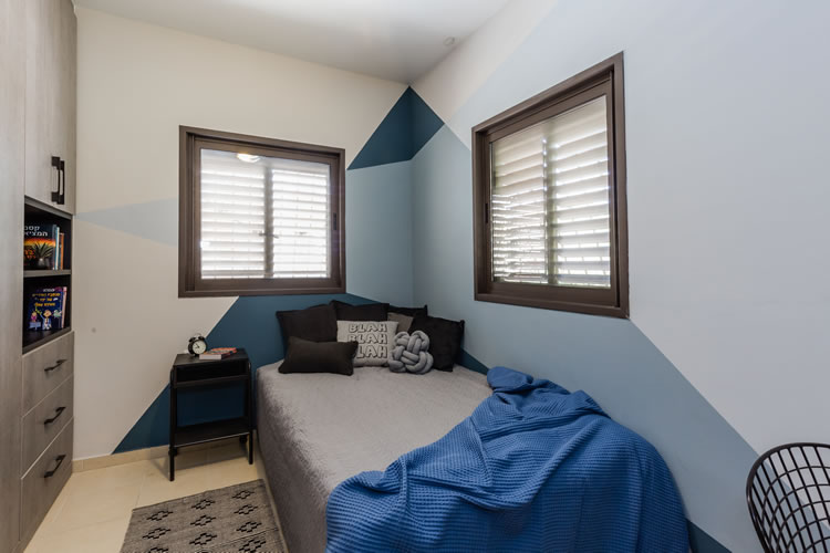 חדר לנער בעיצוב מודרני עם קירות צבועים בדוגמת משולשים.