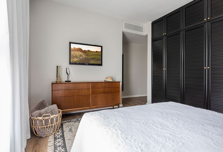 עיצוב חדר שינה אקלקטי- שילוב ארון תריס שחור עם ארונית עץ בסגנון וינטאג'.