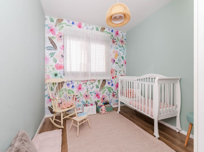 חדר שינה לתינוקת עם טפט פרחוני בעיצוב אישי וקירות בגוון ירוק מרווה.