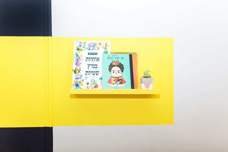 מדף ספרים של איקאה נצבע בגוון הצהוב של הקיר.