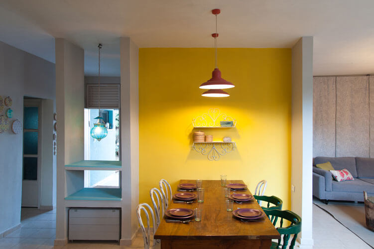קיר צהוב שמש בפינת האוכל משתלב נפלא עם שולחן וכיסאות שליקטנו בשווקי פשפשים. 
